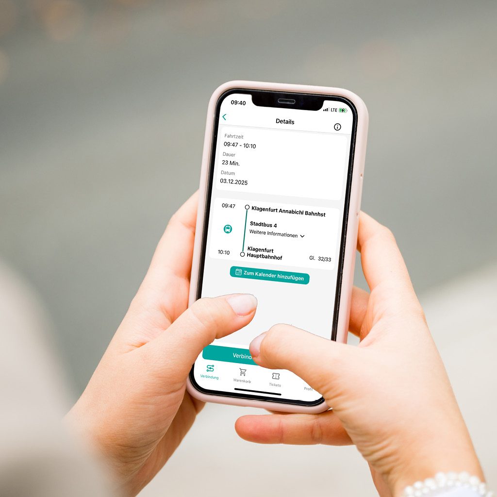 Zwei Hände halten ein Smartphone in der Hand, am Display ist eine Routenabfrage für einen KMG-Bus ersichtlich.