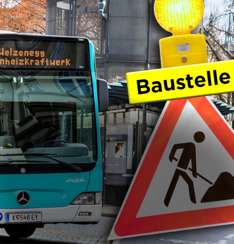 Ein KMG-Bus steht am Heiligengeistplatz an einer Haltestelle. Rechts daneben ist ein Ständer mit einem gelben Warnlicht und einem darunter angebrachten gelben Schild mit der Aufschrift 